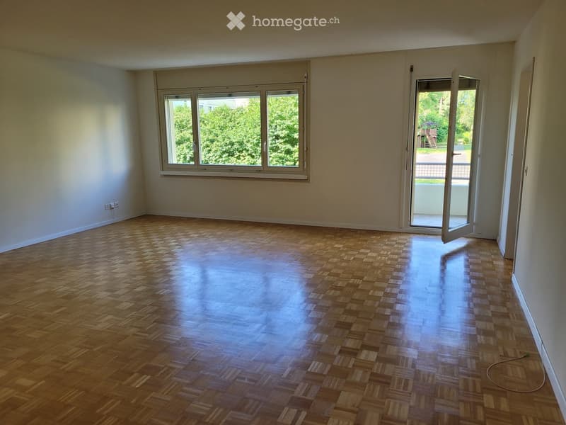 Empty room with wooden parquet flooring, large windows, and an open sliding door leading outside.