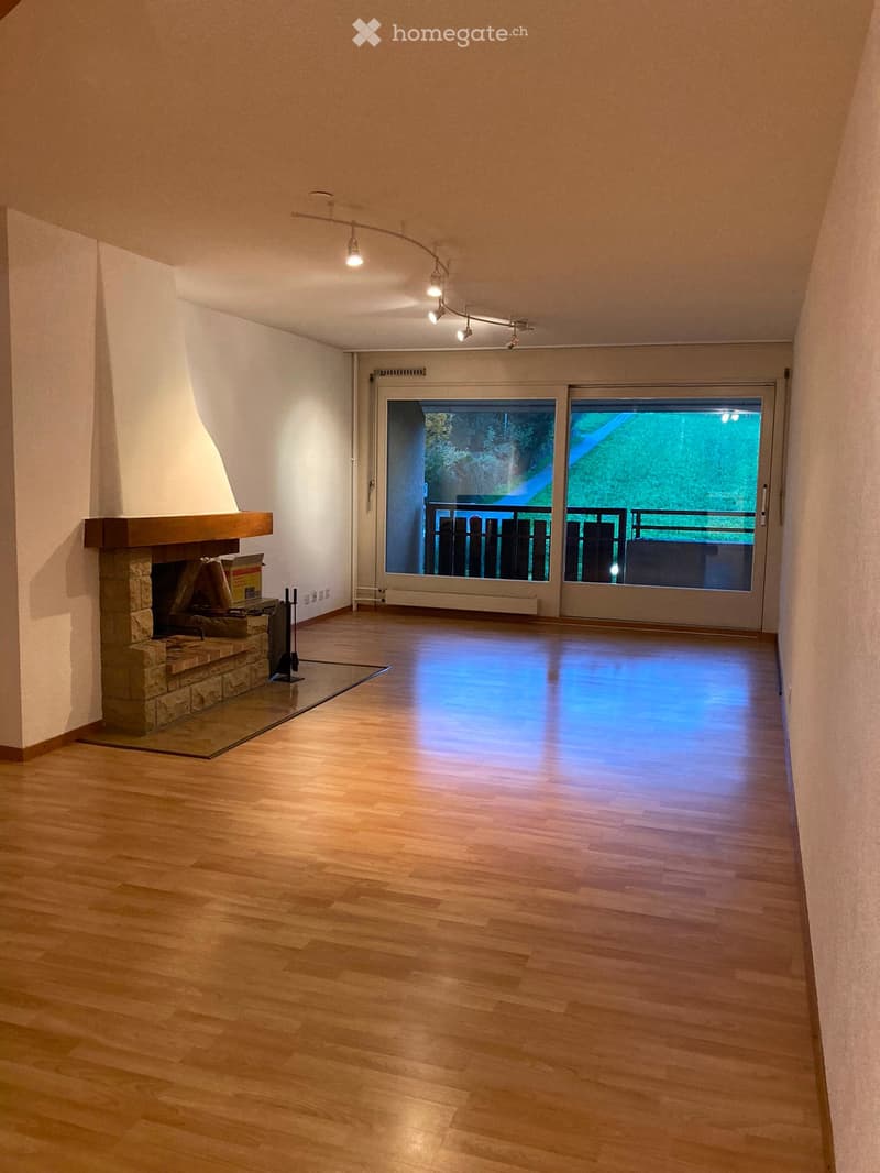 Empty room with wooden flooring, fireplace, and large sliding glass doors leading to a balcony.
