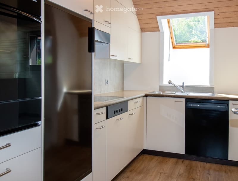 Modern kitchen with light-colored cabinets, stainless steel appliances, and wooden flooring.