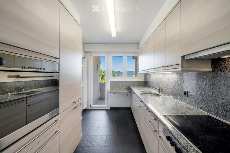 Modern kitchen with stainless steel appliances, granite countertops, and an entrance to the balcony with sliding glass doors.