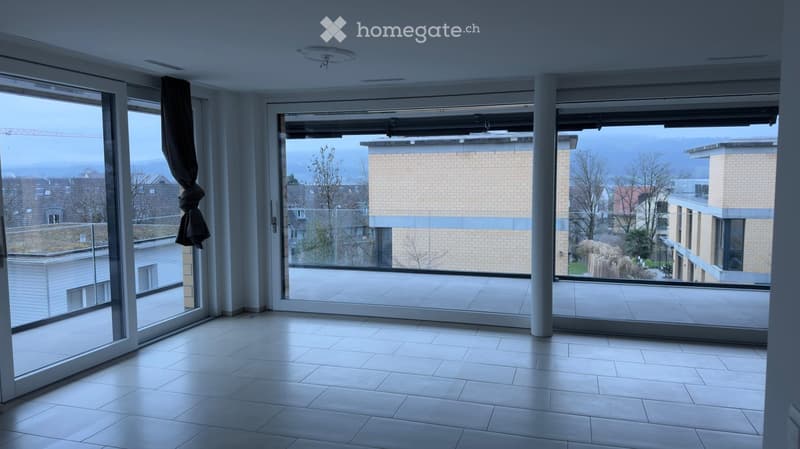 Empty room with large glass doors leading to a balcony, tiled floor, and a view of the cityscape.