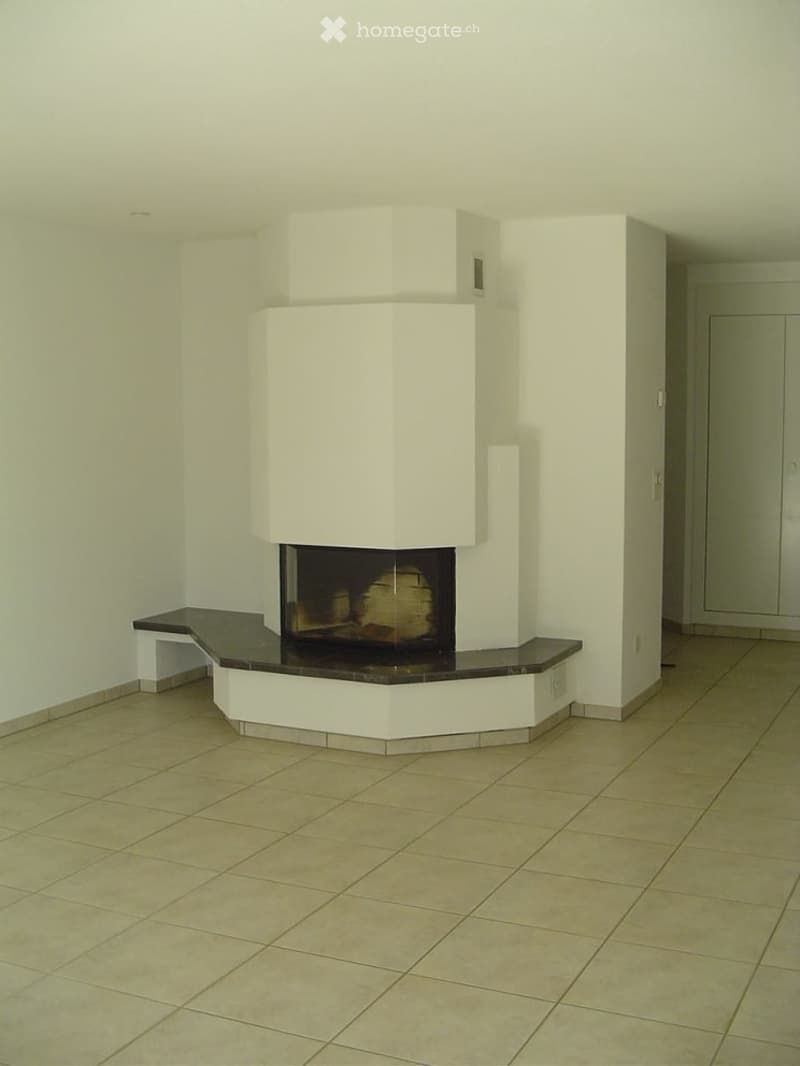 Empty room with a modern white fireplace and tiled floor.