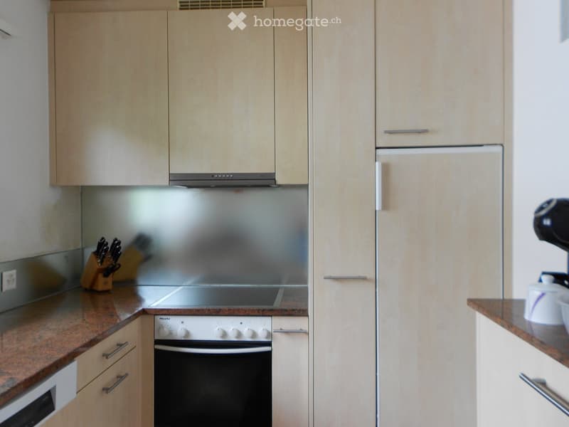 Modern kitchen with light wood cabinets, stainless steel appliances, and granite countertops.