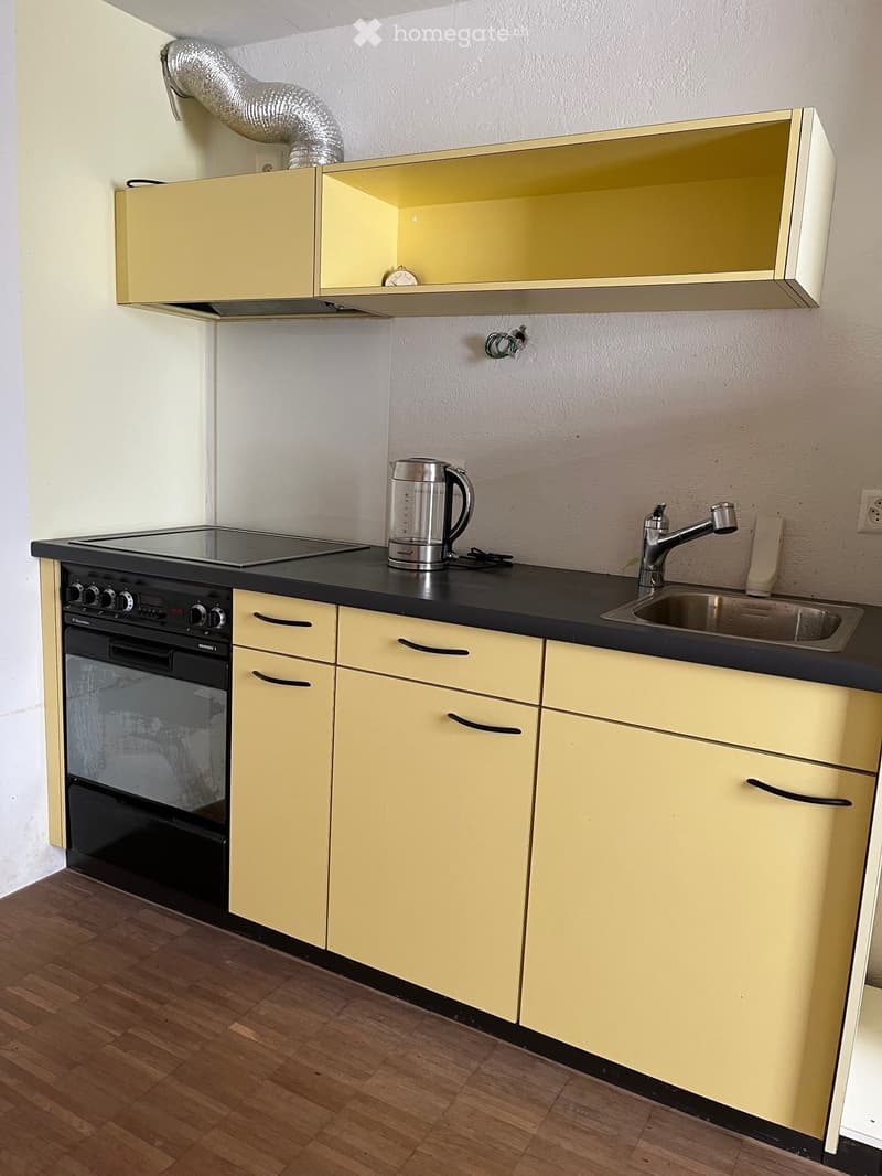 yellow cabinets, black countertop, stainless steel sink, electric stove, kettle, power outlet