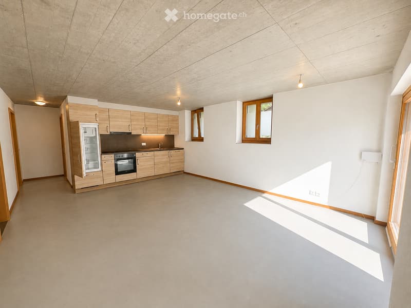 Modern kitchen with light wooden cabinets, stainless steel appliances, and large windows allowing natural light to fill the space.