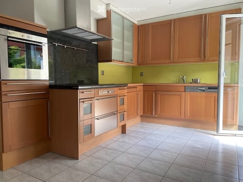 Modern kitchen with wooden cabinets, stainless steel appliances, and a tiled floor.