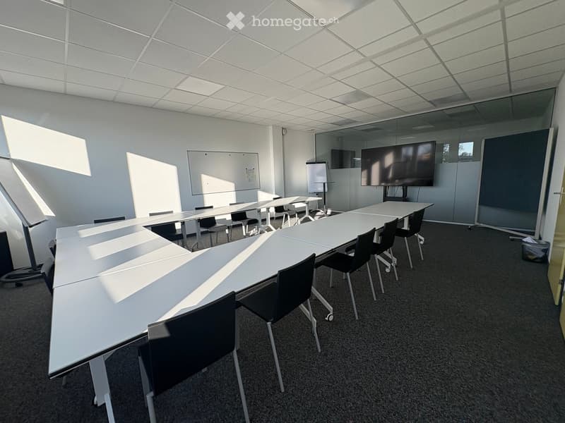 empty conference room with long tables, chairs, whiteboards, and a TV