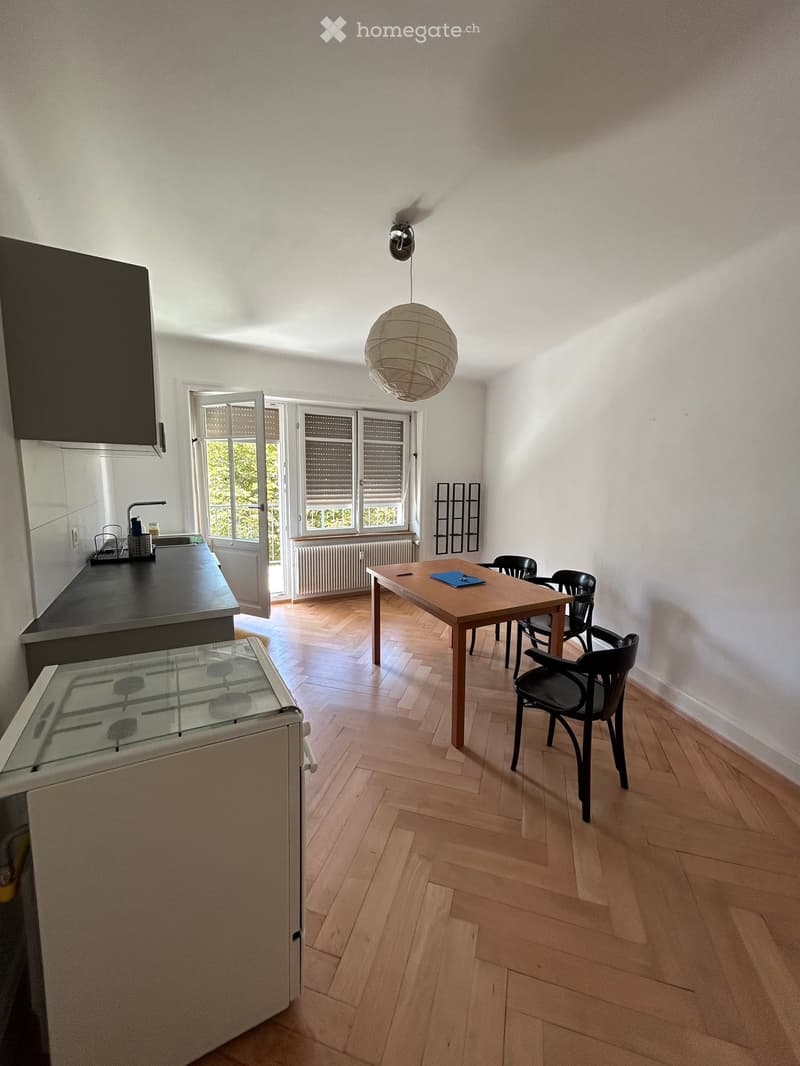 Open-plan kitchen and dining area with wooden flooring, modern appliances, and a dining table with chairs.