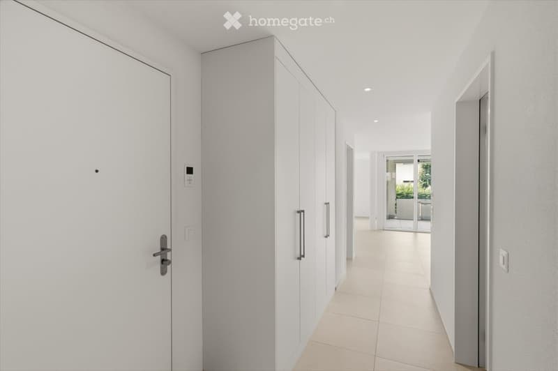 Modern, minimalist hallway with white walls, light-colored tiled floor, and built-in white cabinetry. Features recessed lighting and a sliding glass door leading to an outdoor area.