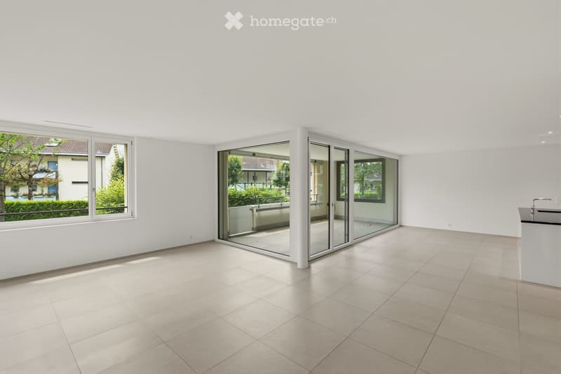 Empty room with white walls, tiled floor, large windows, and sliding glass doors leading to a balcony.