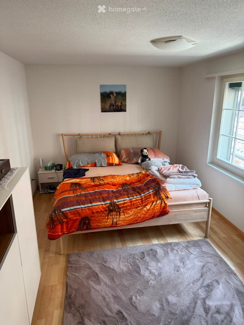 Cozy bedroom with a wooden bed, colorful bedding, a nightstand, and a picture frame on the wall.