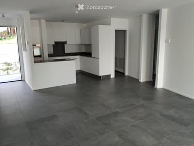 Empty kitchen with white cabinets, dark tiled floor, and a countertop. No furniture or appliances are present.