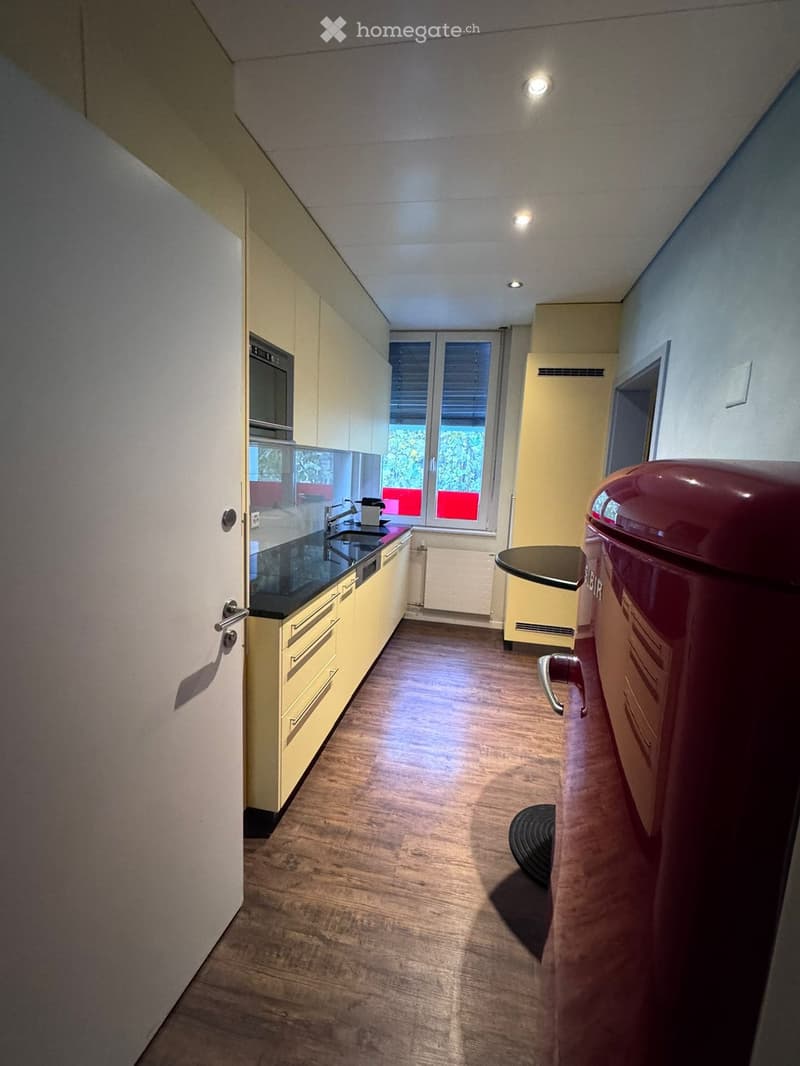 a kitchen with wooden flooring, yellow cabinets, a countertop, a built-in oven, a dishwasher, and a sink with a faucet