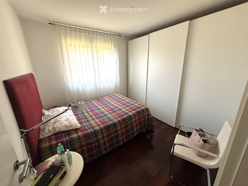 Bedroom with bed, bedside table, chair, curtain, storage cabinets