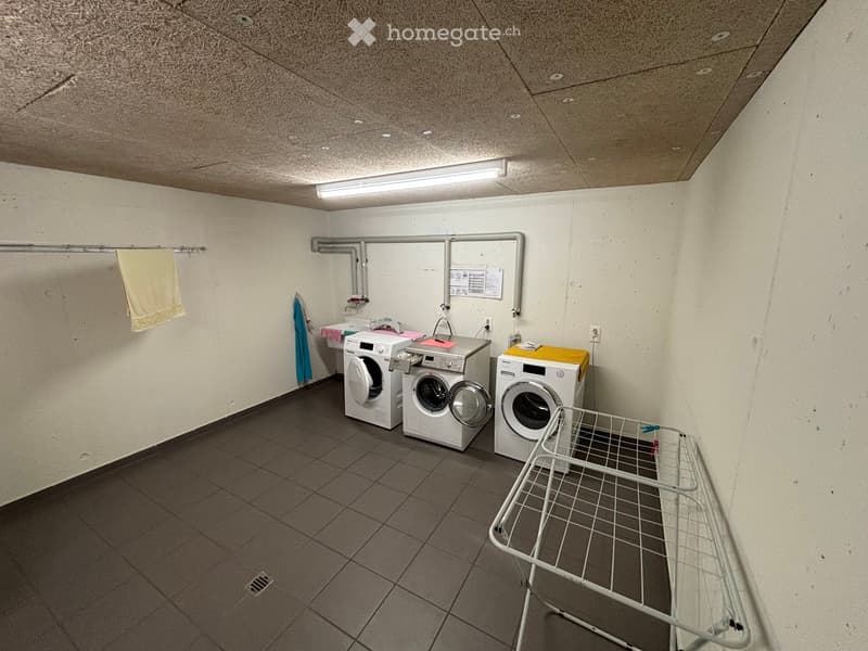 room with three washing machines, drying rack, tiled floor