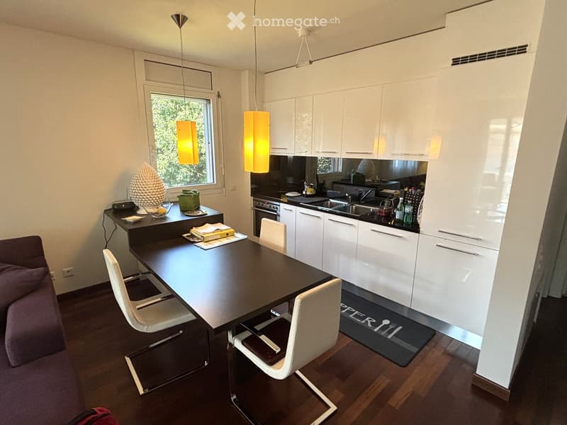 modern kitchen with a dining area, wooden table, white chairs, white cabinets, stainless steel fridge, sink with faucet