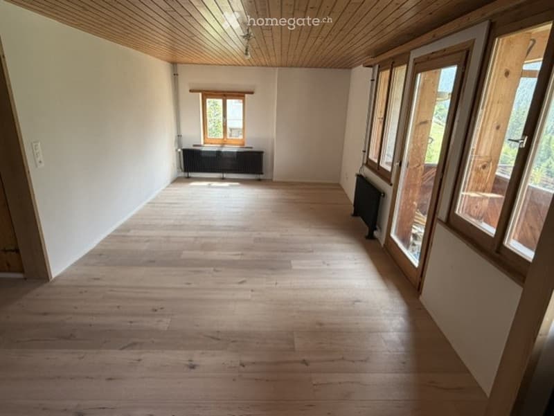 Completely empty room with wooden flooring, white walls, and large windows. No furniture or equipment.