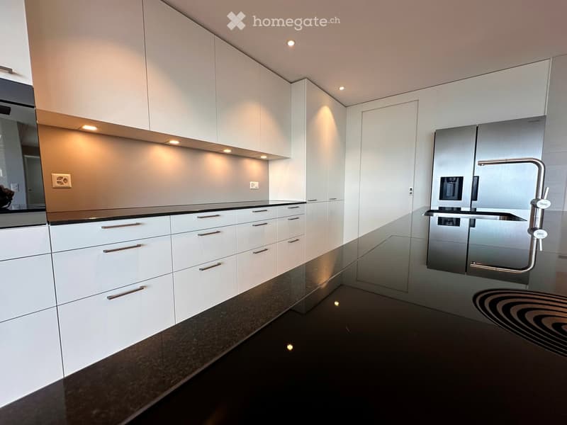 modern kitchen with white cabinets, black granite countertops, stainless steel refrigerator, and a sink with a faucet