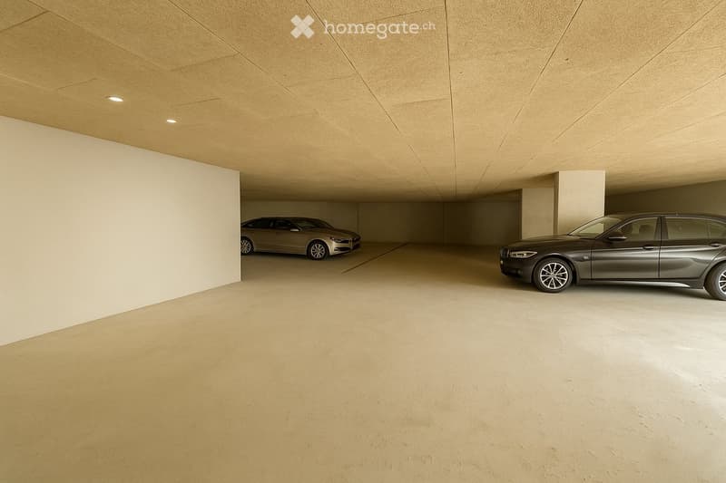 Modern underground garage with two parked cars, beige walls, and a smooth concrete floor.