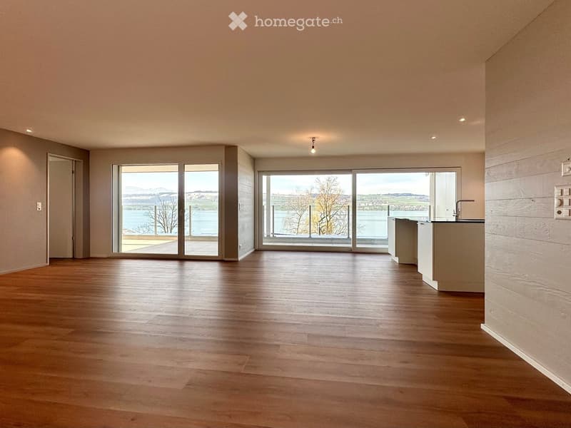 large open space, wooden floor, sliding glass doors, kitchen island, view of the lake