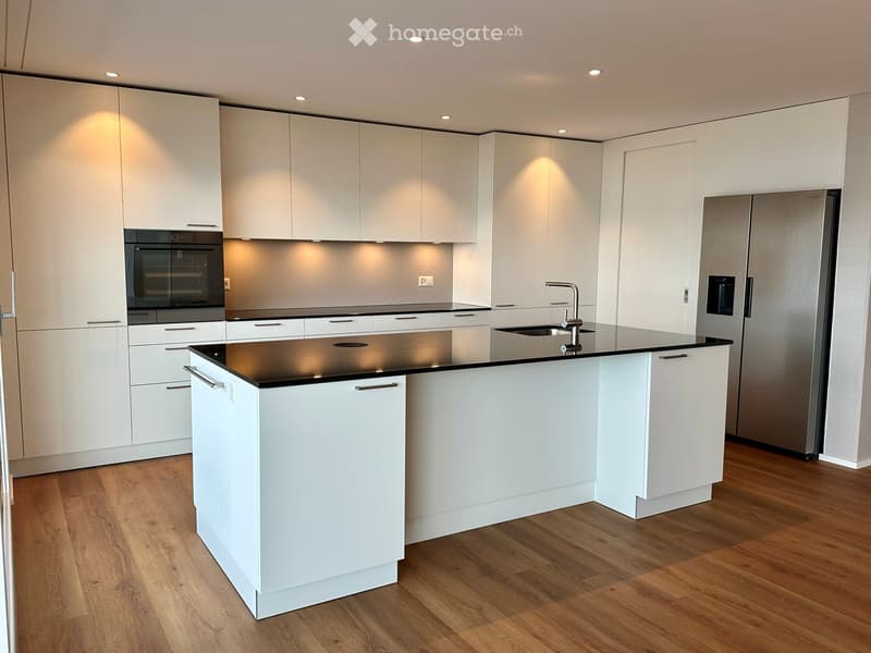 modern kitchen with white cabinets, black countertops, stainless steel refrigerator, dishwasher, oven, island with sink and faucet