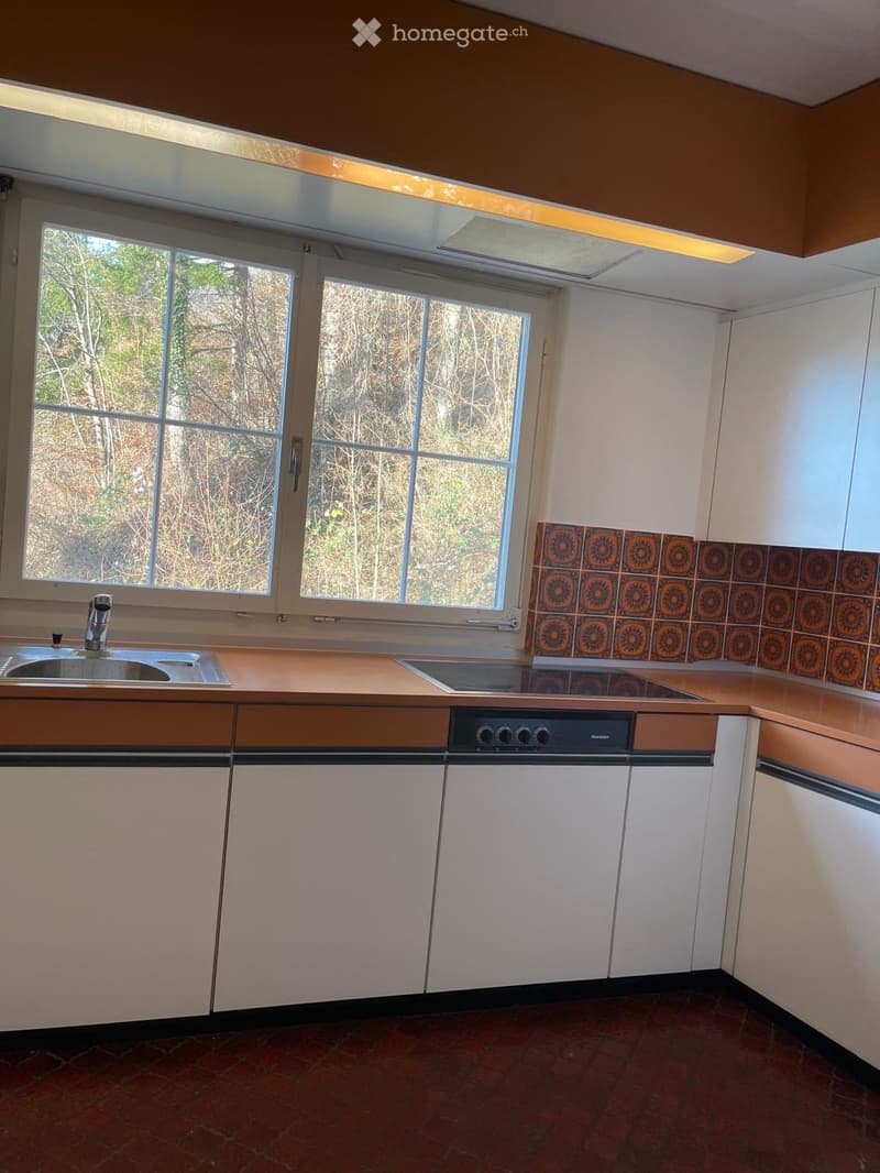 Modern kitchen with white cabinets, brown countertop, stainless steel sink, dishwasher, electric stove, tile flooring, large window