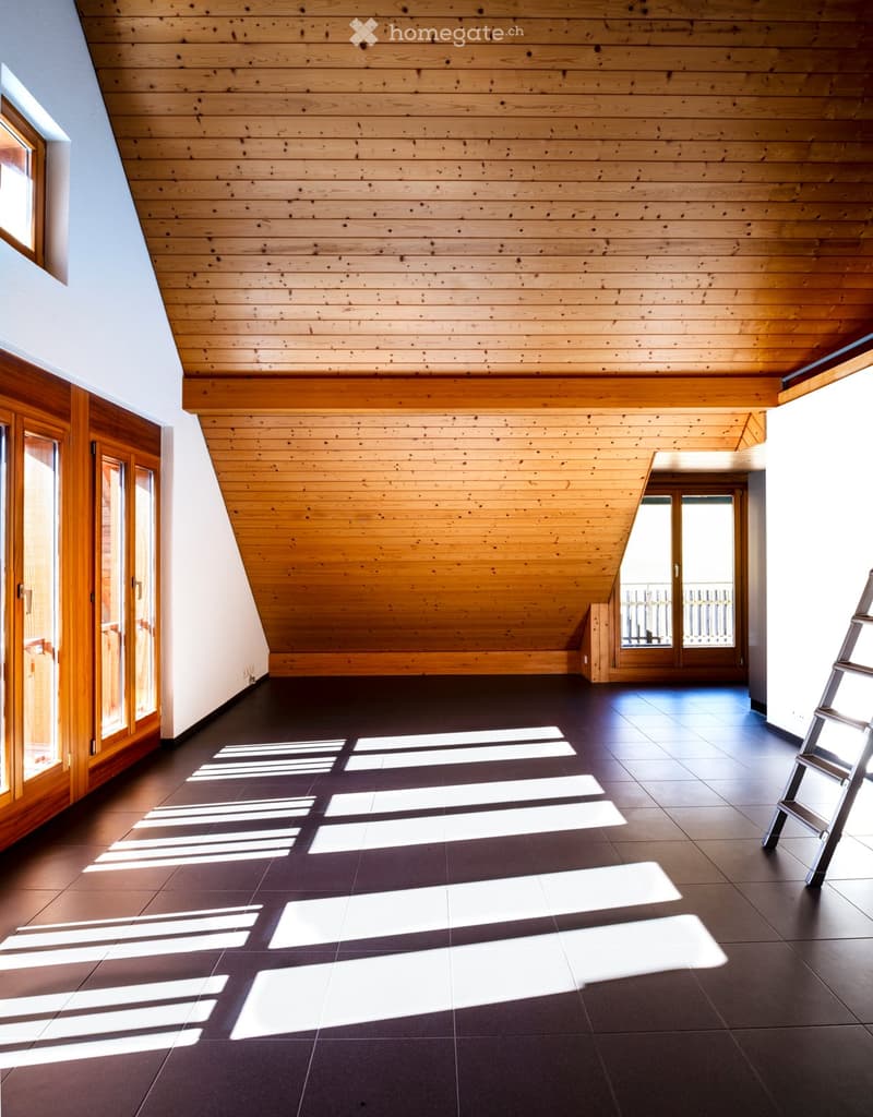 Empty room with wooden ceiling, dark tiled floor, large windows, and wooden doors.