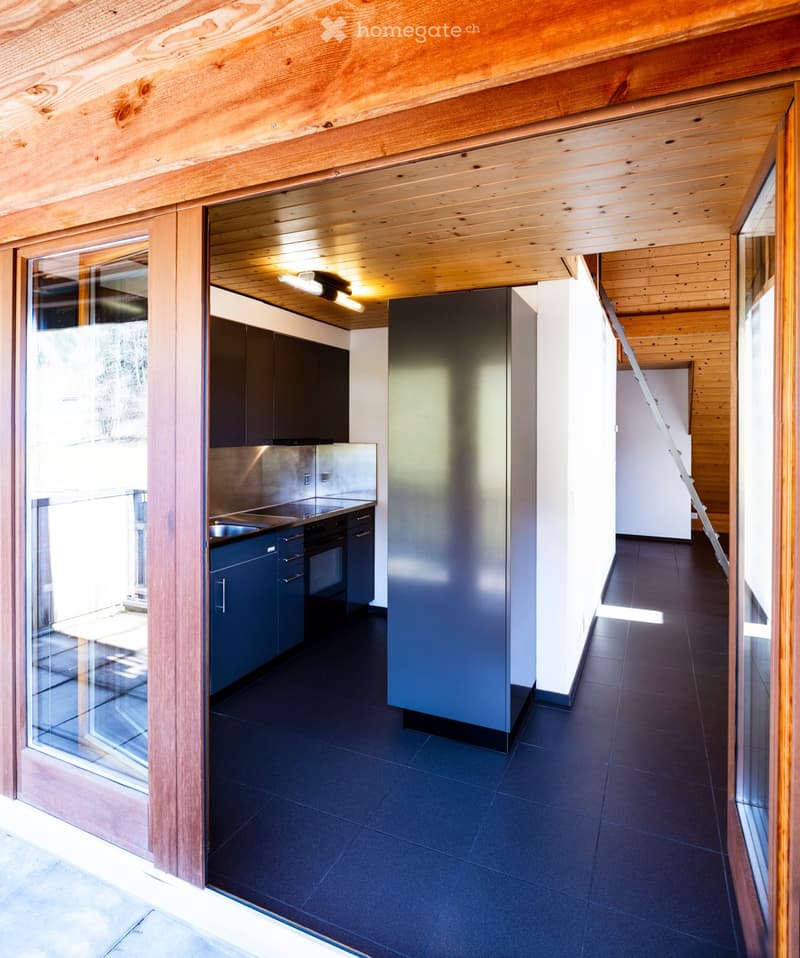 Modern kitchen with dark blue cabinets, stainless steel appliances, and a sleek black tiled floor.
