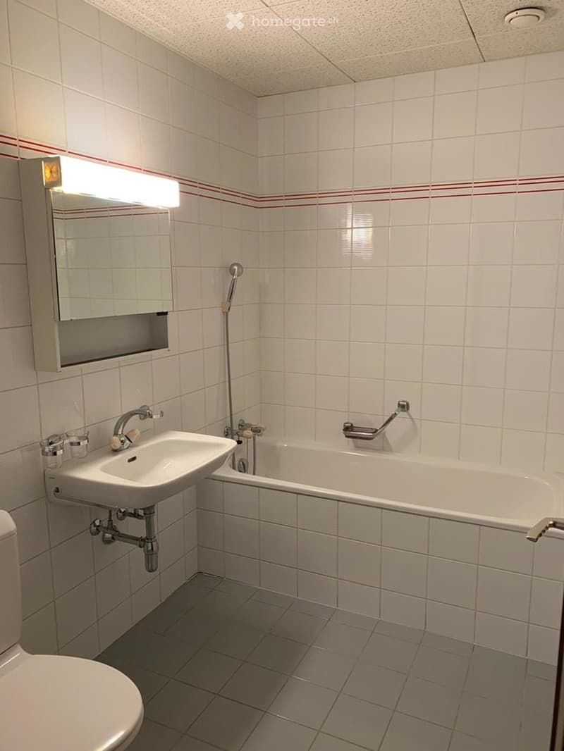 white tiled walls, white tiled floor, bathtub, sink, toilet, mirror, under-mirror cabinet