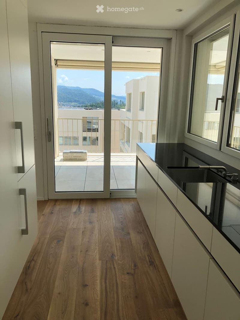 Hallway with wooden flooring, sliding glass doors leading to a balcony with a scenic mountain view.