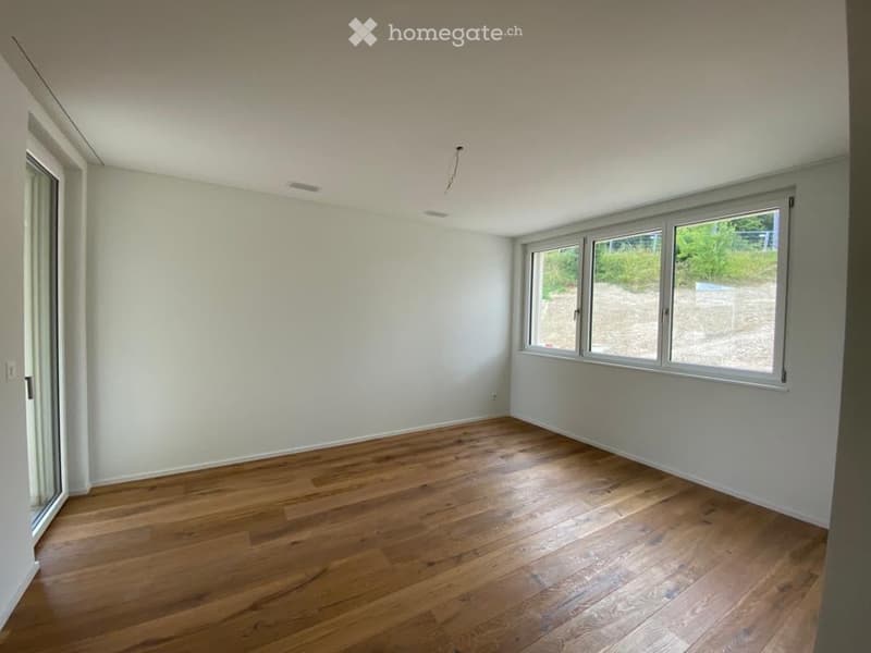 Empty room with wooden flooring and large windows, no furniture or equipment.