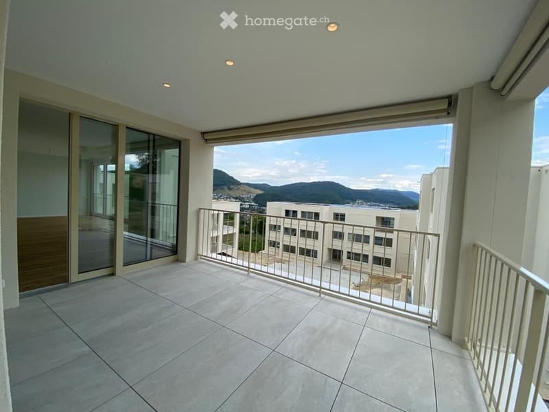 Spacious balcony with tiled flooring, modern metal railings, large glass sliding doors, and scenic mountain view.