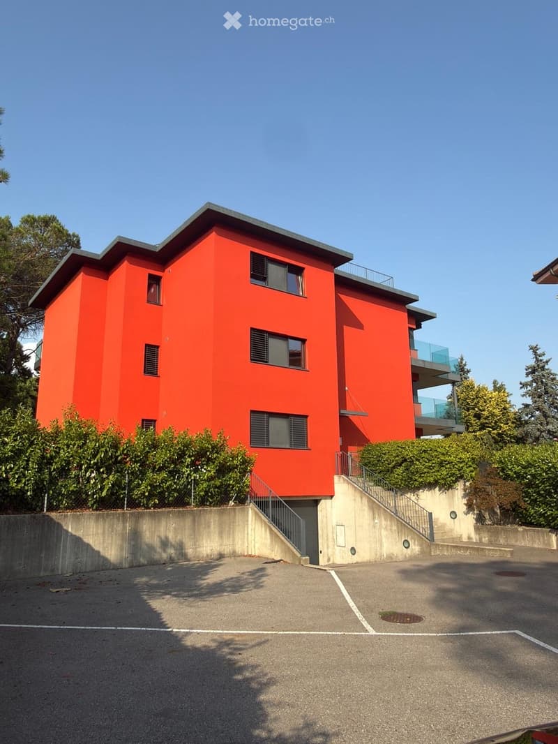 Modern two-story house with bright orange exterior, multiple windows, and a raised ground floor accessed by stairs.