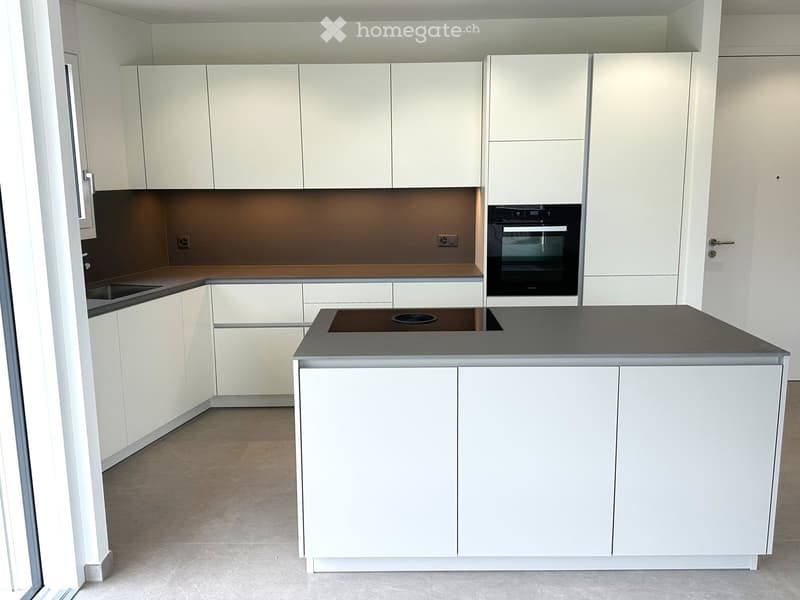 Modern kitchen with white cabinets, a central island, and built-in appliances including an oven and sink.