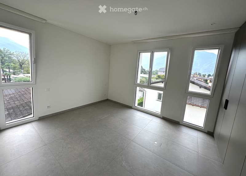 Empty room with large windows offering a scenic mountain view, tiled floor, and white walls.