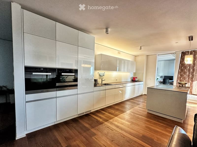 Modern kitchen with white cabinetry, stainless steel appliances, wooden flooring, and an island with seating.