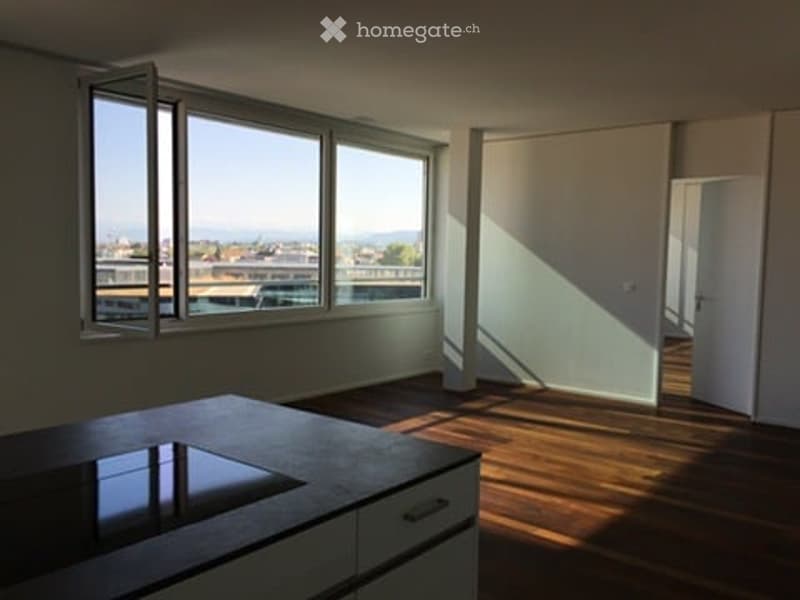 Bright, modern kitchen with a large island, white cabinets, and expansive windows offering a city view.