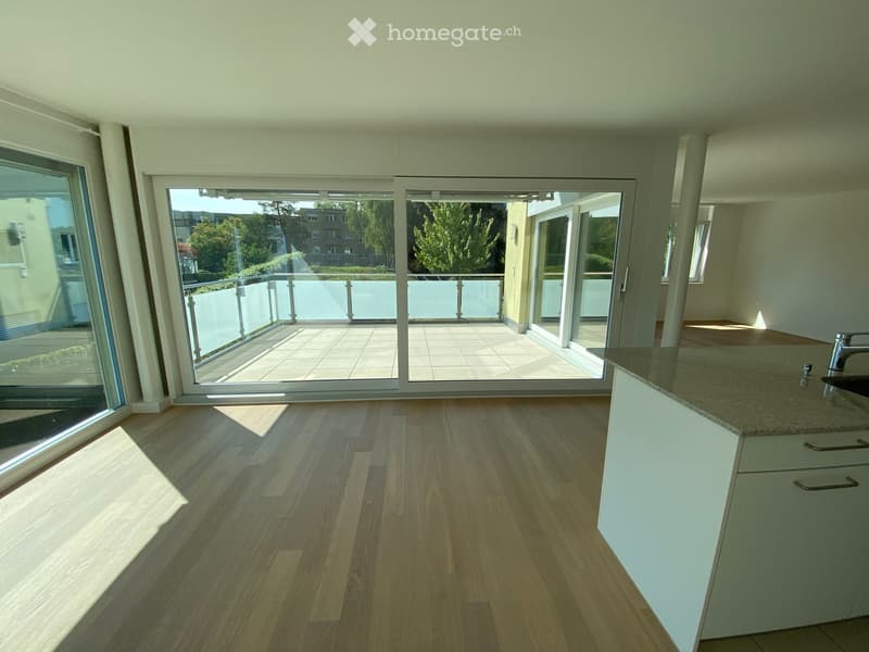 Empty room with wooden flooring, white cabinets, and large sliding glass doors leading to a balcony.