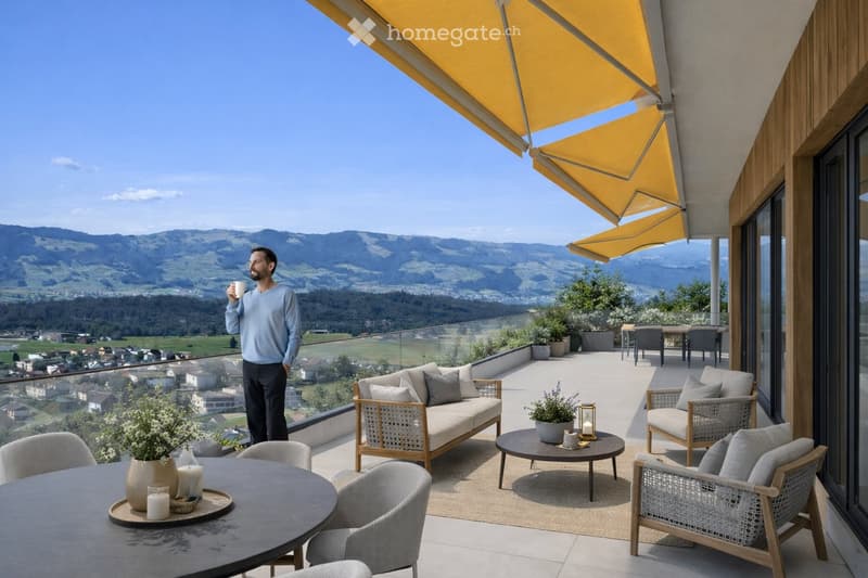 A spacious balcony with a scenic mountain view, furnished with a sofa, chairs, coffee table, and decorative items.