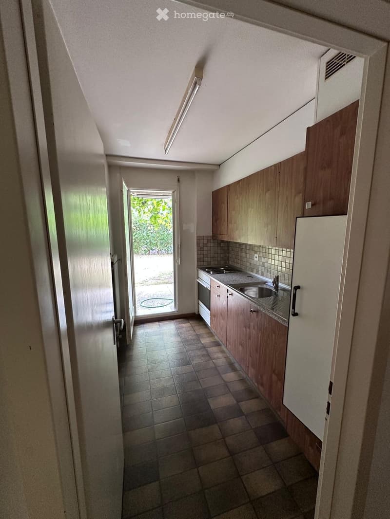 Modern kitchen with wooden cabinets, tiled floor, sink, and oven. Features a sliding glass door leading to an outdoor area.