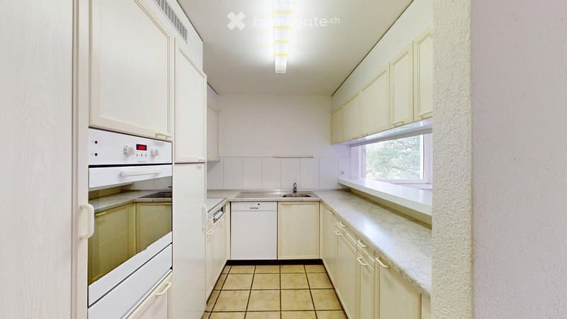 Bright kitchen with white cabinets, granite countertops, and stainless steel appliances including a refrigerator, oven, and dishwasher.
