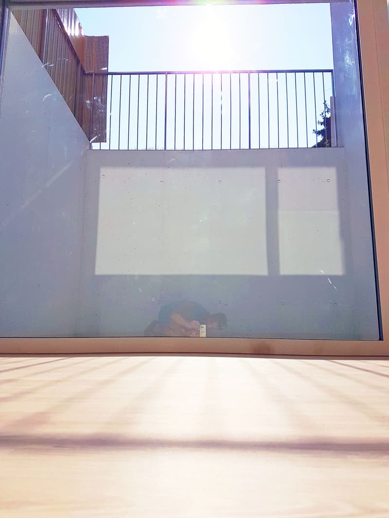 Balcony with a glass door, metal railing, and wooden floor, offering a view of the outside area.