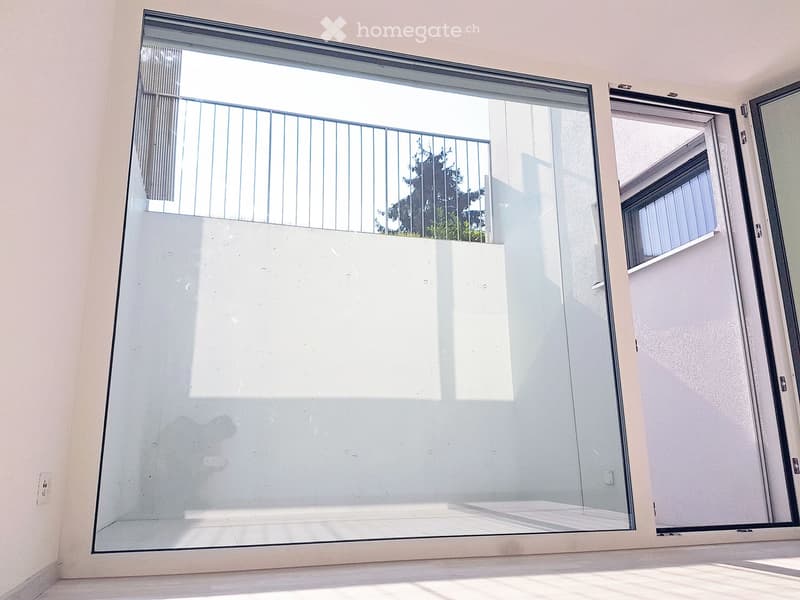 a room with a large glass wall with a balcony and a door