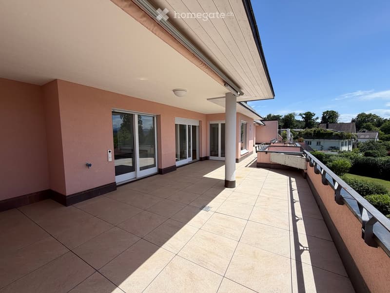 Balcony with tiled floor, white sliding doors, and a view of greenery and neighboring houses.