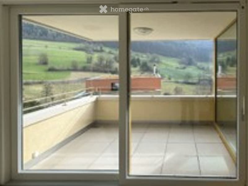 Balcony with large glass doors, tiled floor, scenic countryside view.