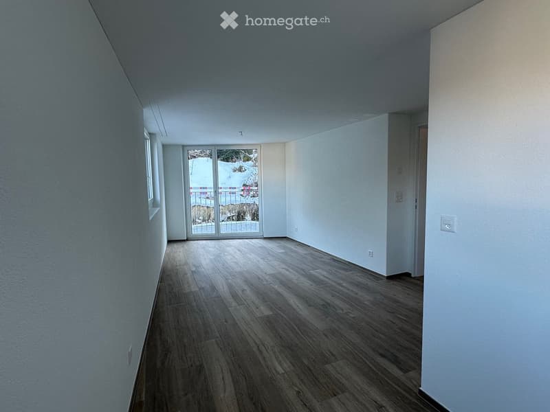 Empty room with wooden flooring, white walls, and a large sliding glass door leading to a snowy outdoor area.