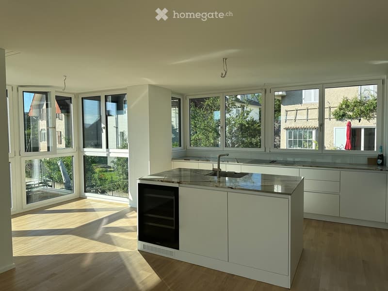 Modern kitchen with white cabinets, a central island, and large windows letting in natural light.