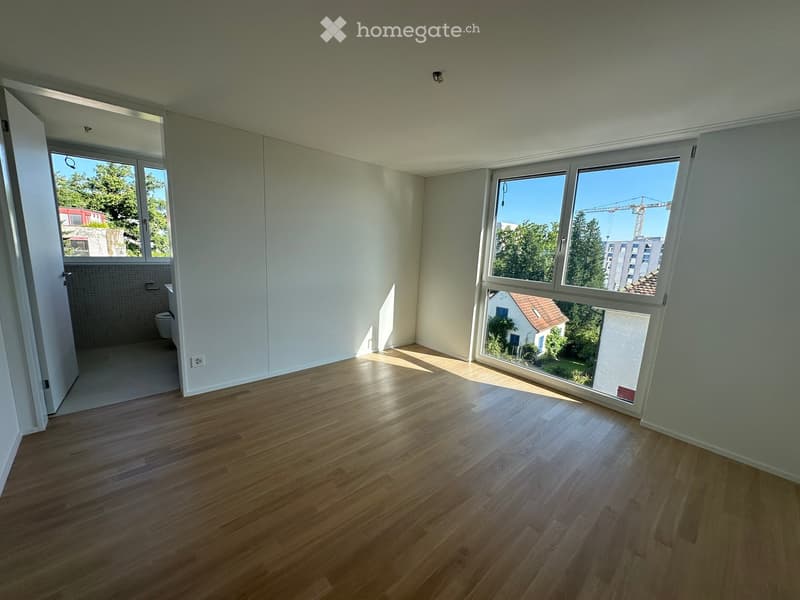 Empty room with wooden flooring, large windows, and a view of the outside. The room is unfurnished with no visible furniture or equipment.