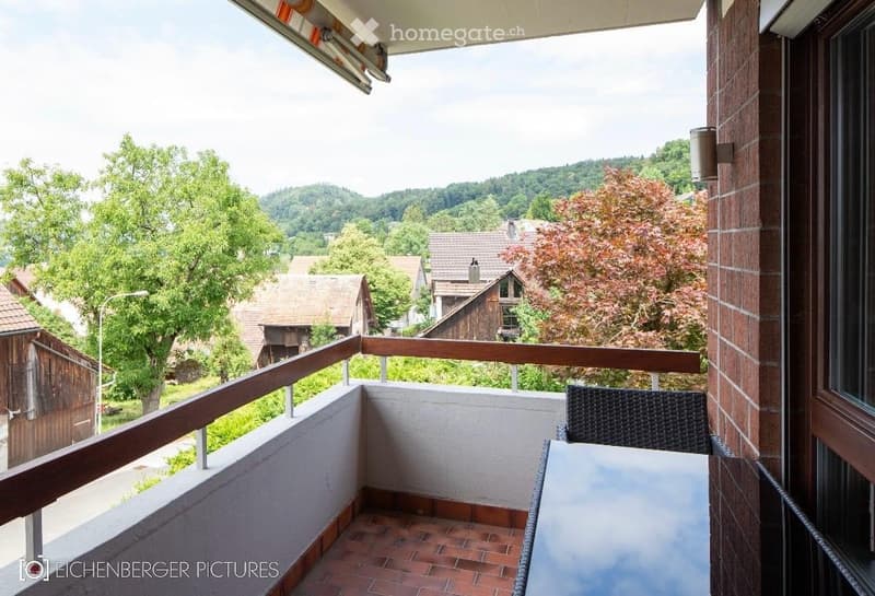 Balcony with a view of a rural landscape, featuring a table and a chair.