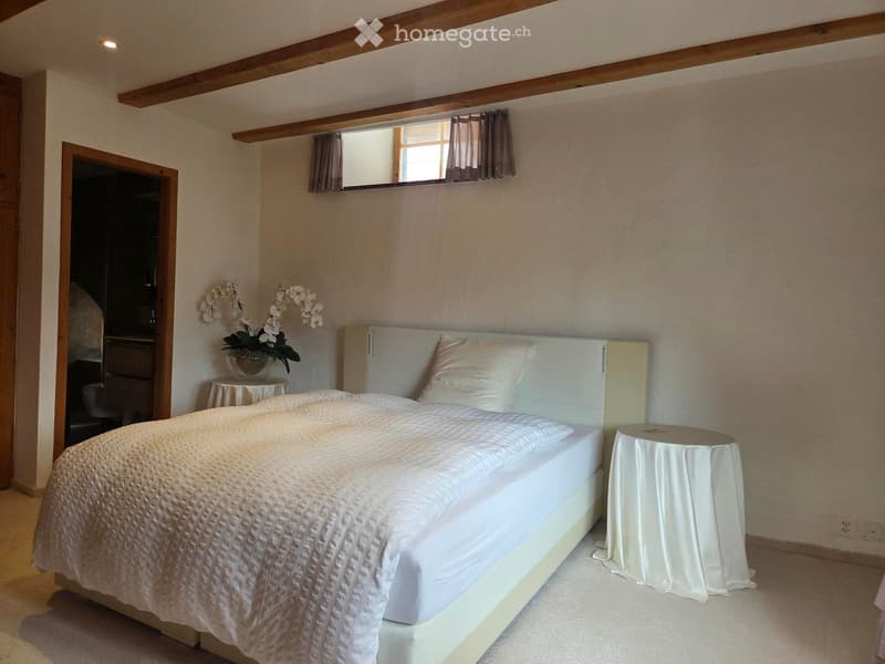 Cozy bedroom with a large bed, nightstands, a flower vase, and a mirror above the bed.